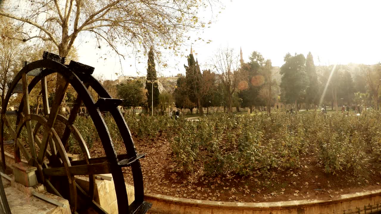 el molino de agua se mueve la puesta del sol brilla en los céspedes de flores urfa