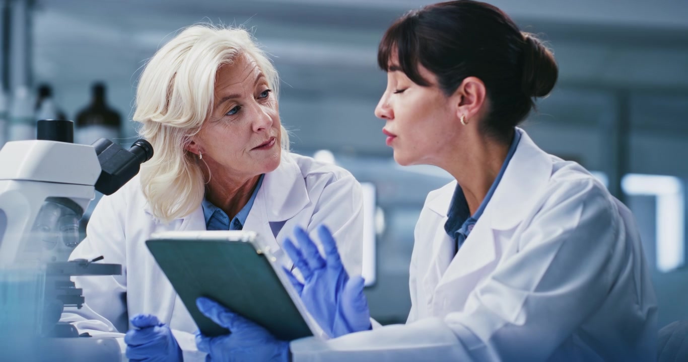 Due Scienziate Discutono Dati di Ricerca su un Tablet in Laboratorio