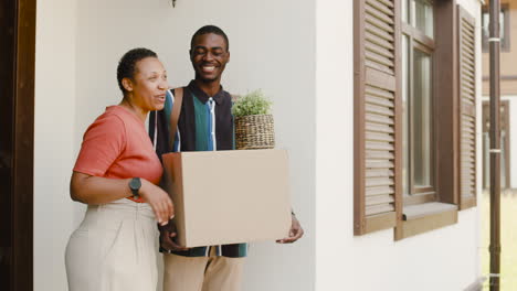 young man holding box and talking with his mom before moving home