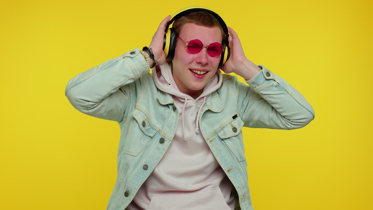 Glad og attraktiv mand, der lytter til musik via hovedtelefoner og danser disco og fjoller rundt og har det sjovt