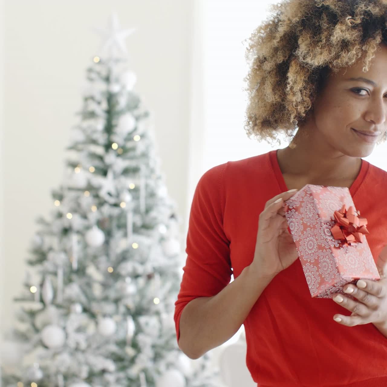 mujer sonriente sosteniendo un regalo de navidad