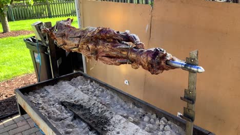 A-lamb-roasting-on-a-spit-on-an-electric-grill,-in-a-backyard