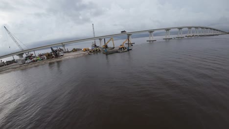 Establishing-drone-shot-flying-over-Sanibel-Island-Causeway,-Florida-as-first-work-trucks-head-towards-island