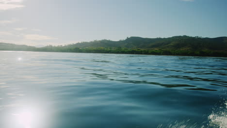 Sparkling-shimmering-light-of-sun-across-dreamy-ocean-water-with-tropical-background