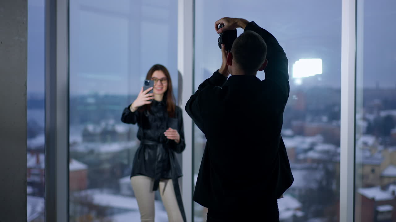 Fotograf tager billeder af en model i et studie med byudsigt