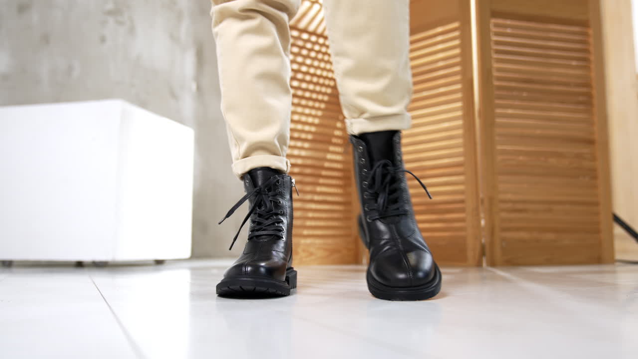 Woman wearing black lace-up boots and beige pants