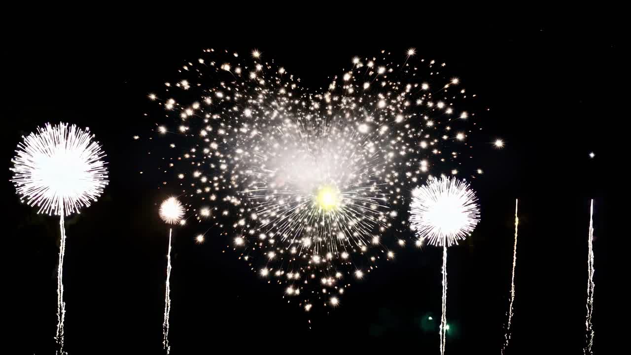 Aerial video captures heart-shaped fireworks exploding in the night sky, viewed from a low angle
