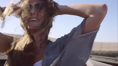 beautiful girl on adventure road trip in vintage convertible enjoying the wind in her hair