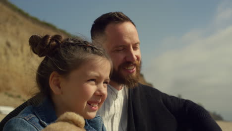 familia sonriente disfrutando de un picnic en la playa de arena del mar. papá niña divertirse en un día soleado