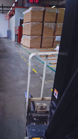 Production of wooden parquet. Piles of parquet boards inside the factory of furniture industry. View from forklift cart. Vertical video