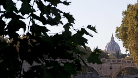 Saint-Peter's-dome-in-background-in-distance-with-tree-leaves-in-foreground-during-sunset-in-Rome