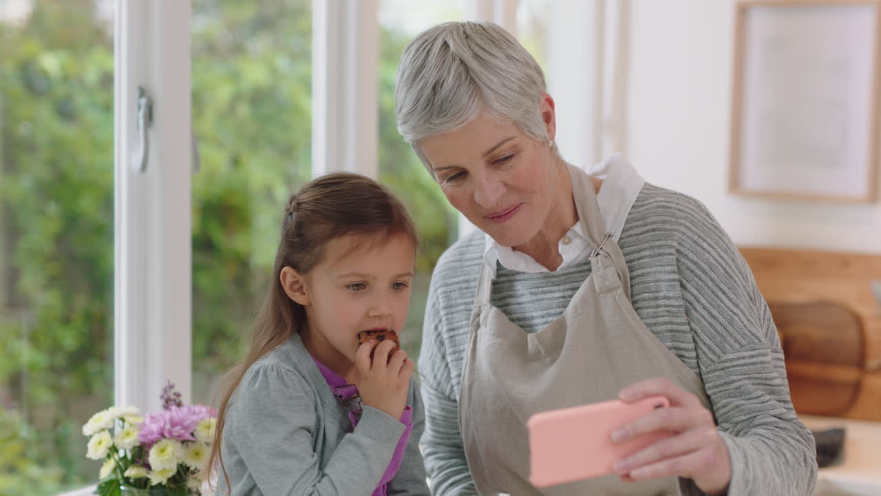 할머니와 아이가 스마트폰을 사용하여 비디오 채팅을 하고 있습니다. 작은 소녀는 할머니와 함께 휴가 주말을 공유하고 손녀와 함께 집에서 휴대폰으로 채팅을 즐기고 있습니다.