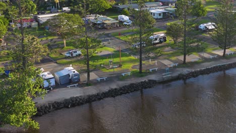 aerial footage captures a serene riverside campground with caravans and lush greenery in brunswick heads, nsw, australia