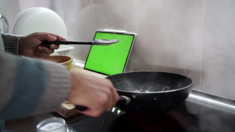 over the shoulder shot of a man cooking sepia using a recipe from his tablet