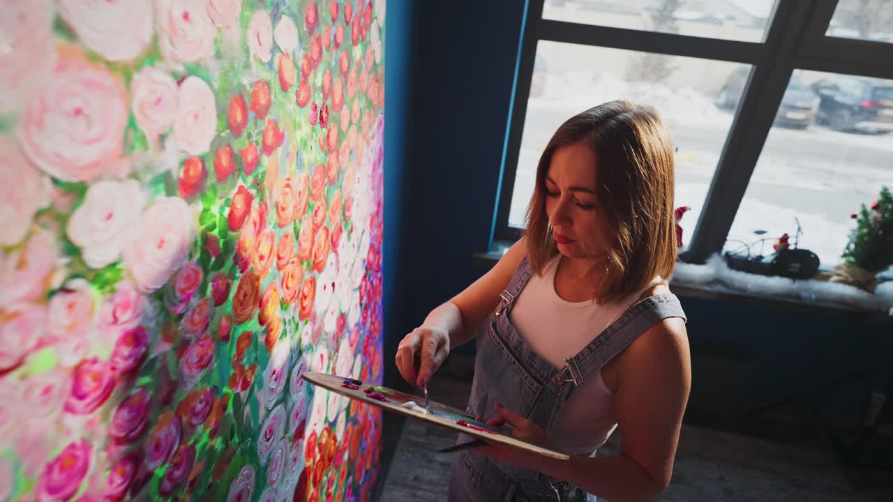 Artista donna che dipinge un'opera floreale vibrante su una grande tela