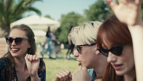 group of friends sitting together on the grass and dancing at music festival