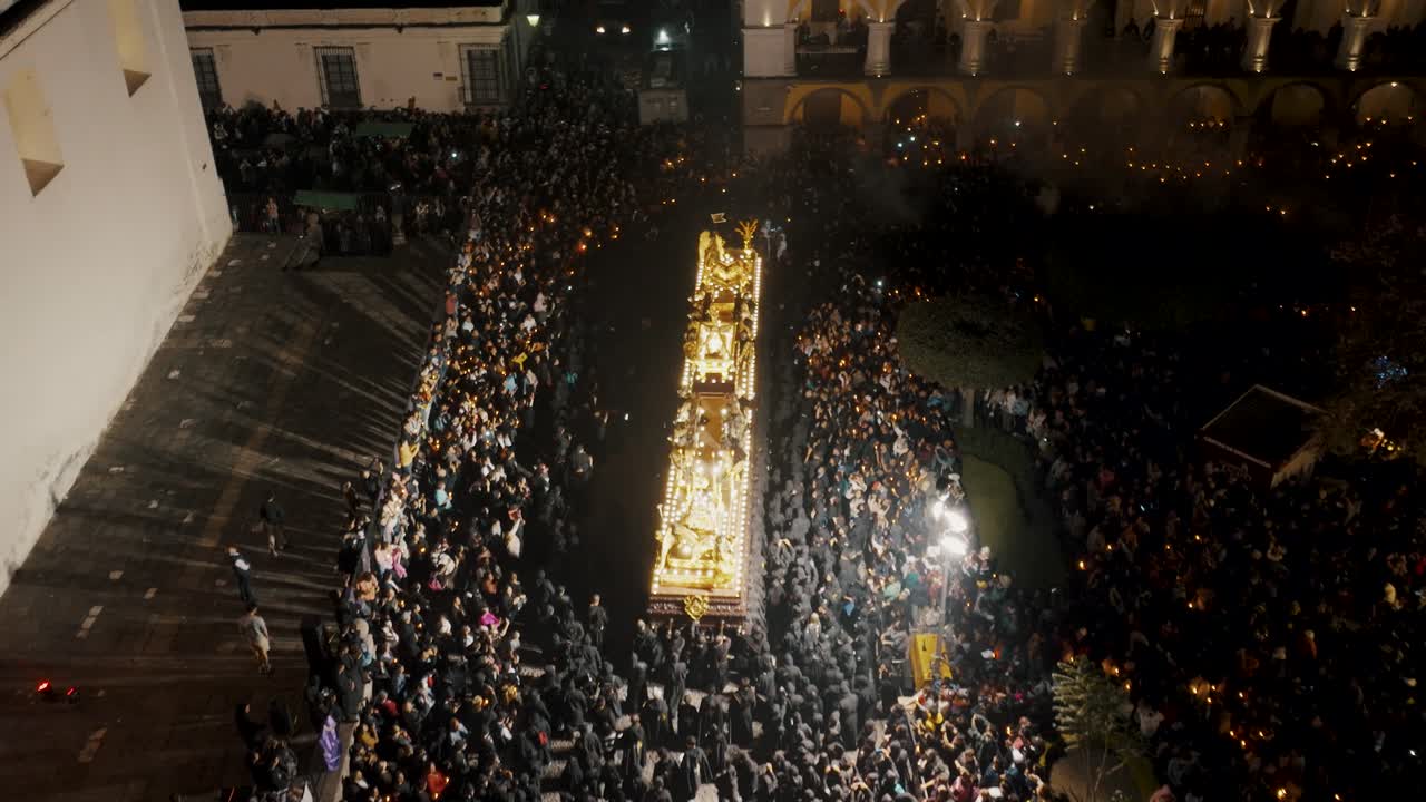 cientos de cucuruchos personas en túnica llevando y flotando frente a la catedral antigua de guatemala por la noche durante las procesiones