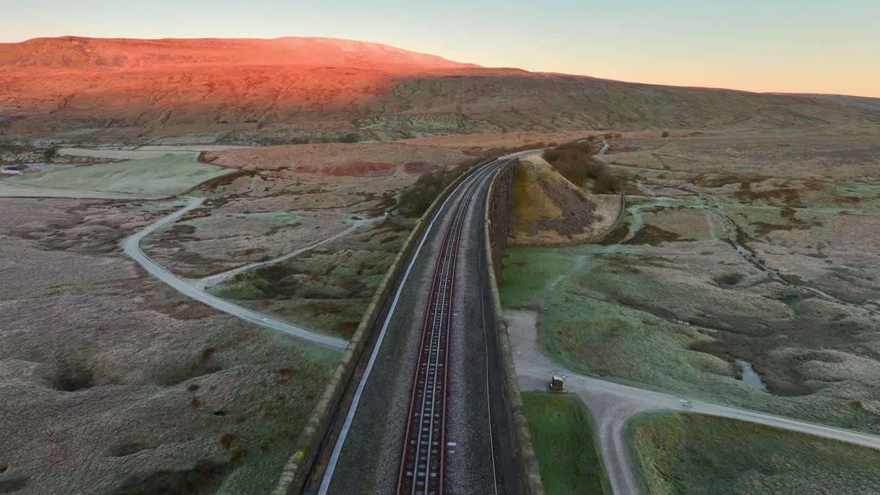 겨울에 새벽에 영국 습지를 가로지르는 철도 다리 위의 단일 트랙