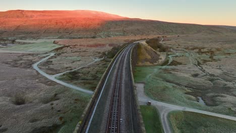 vía única en el puente ferroviario sobre el páramo inglés al amanecer en invierno