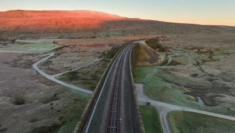 single track on railway bridge over english moorland at dawn in winter