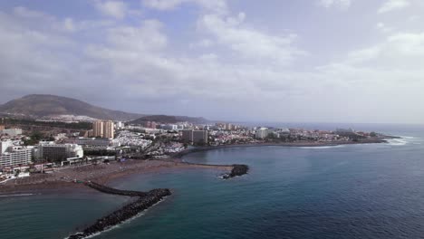 Luftaufnahme-Einer-Kurstadt-An-Einem-Schwarzen-Sandstrand-In-Der-Bucht-Von-Teneriffa