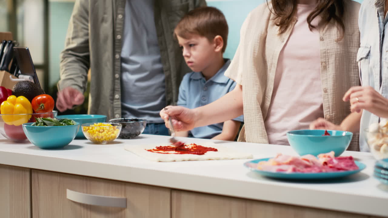 Cheerful family teaches kids to make homemade pizza together in a bright kitchen