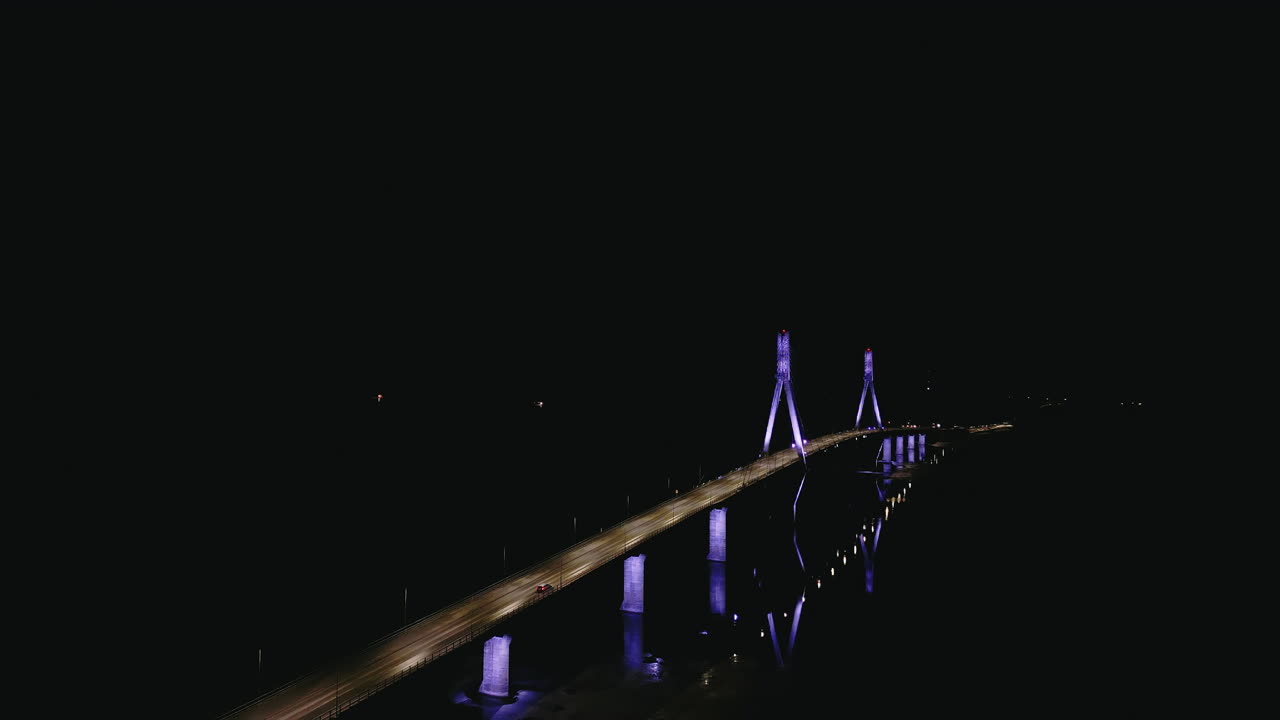 fotografía aérea nocturna de un puente iluminado en finlandia, un automóvil conduciendo en