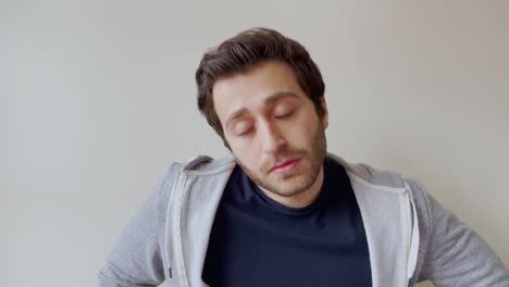 young male student visibly bored whilst looking directly into camera during remote lecture