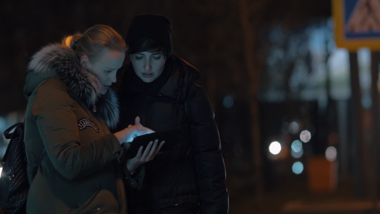 Traffico cittadino notturno e donne con un tablet