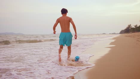 teenager playing with a soccer ball on the beach at sunset