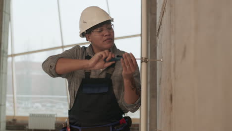 trabajadora atornillando tubos a la pared