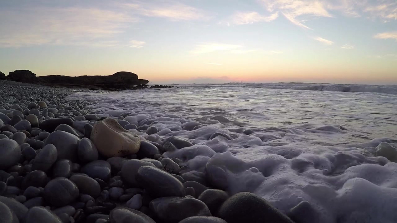 Vagues matinales déferlant sur une plage de galets.