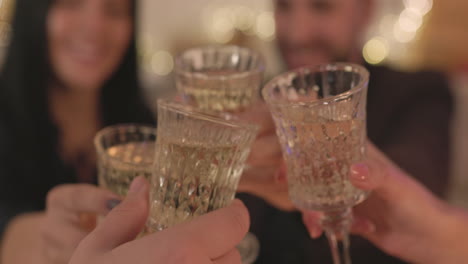 close up of group of happy friends sitting at table and making a toast before eating christmas meal at home