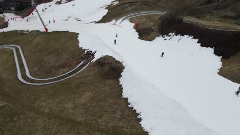 Skiers-and-snowboarders-going-down-the-last-remaining-snow-on-slopes-in-Morzine,-France