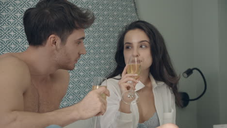 cute couple chilling in hotel room. joyful lovers holding glasses of champagne.