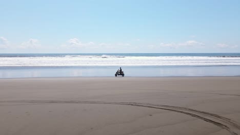 man riding a scooter along a long empty beach in central america