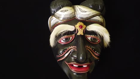 traditional wooden mask of a black old balinese man, indonesia asian black background