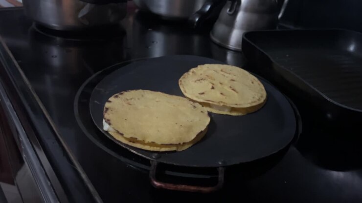 Traditional Honduran pupusas being hand pressed and cooked on a hot comal, showing authentic street food preparation, local cuisine, and cultural cooking techniques in Central America