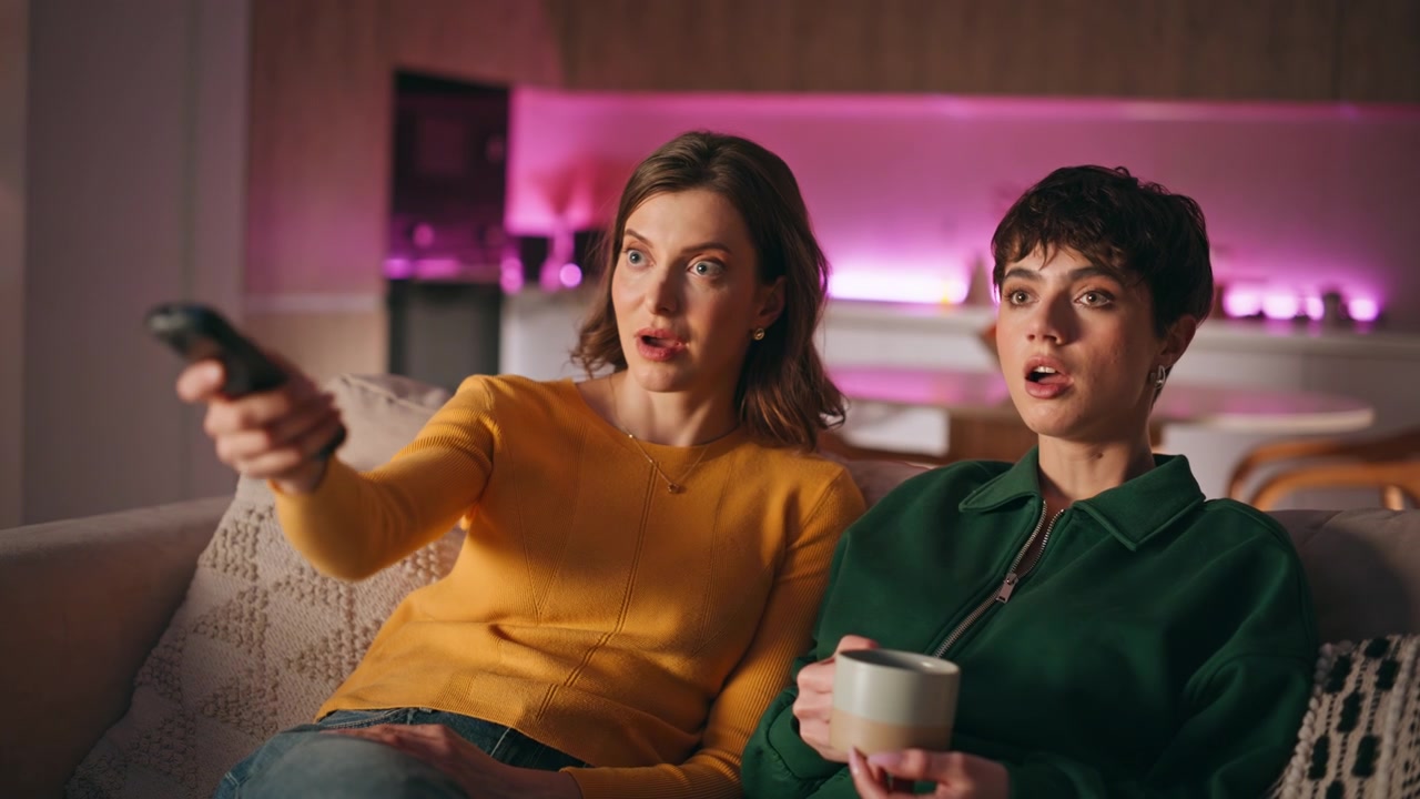 Søstre vælger tv-film, skifter kanaler, sidder sammen på hyggelig sofa