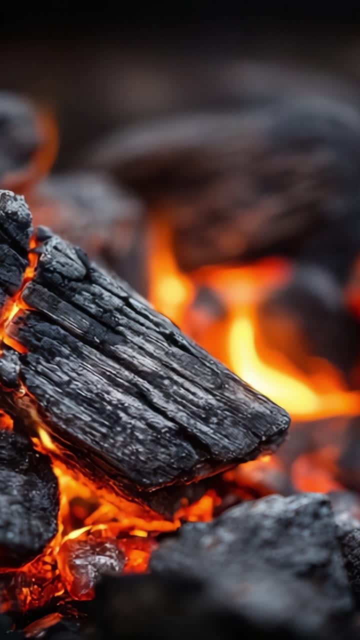 Una vista ravvicinata di braci ardenti di carbone: la trasformazione infuocata del legno in carbone in un falò, che irradia calore ed energia.