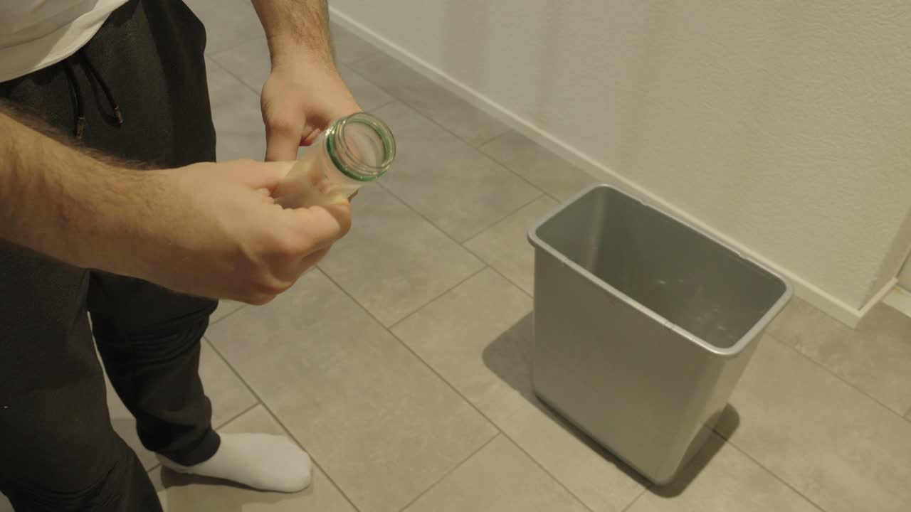A man throws an empty PET bottle into a recycling bin — concept of recycling, waste separation, and environmental awareness