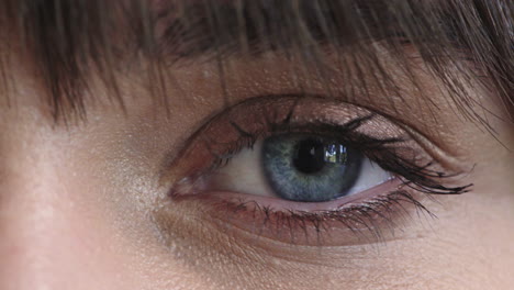 mujer de cerca con los ojos azules abriéndose mirando a la cámara cosméticos de maquillaje