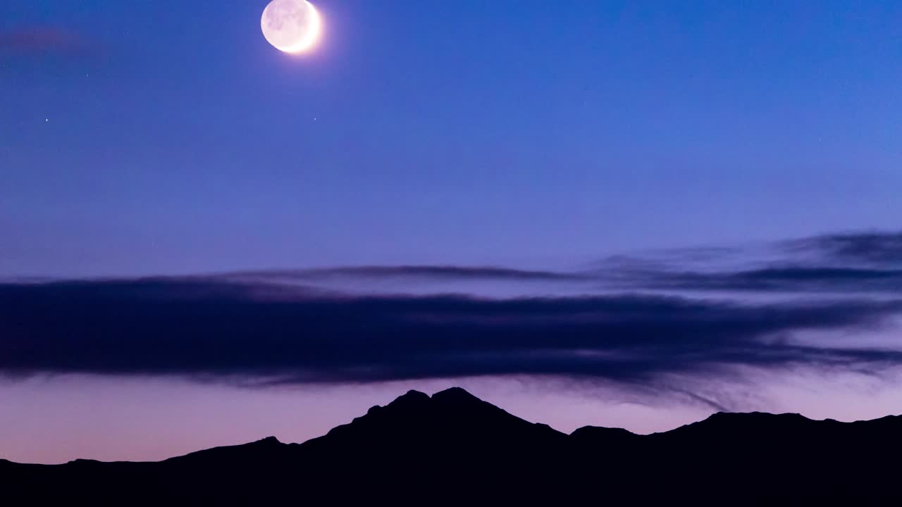 luna crepuscular de 4.000 metros situada en un cielo azul oscuro y profundo sobre la cordillera de silueta negra y un paisaje de nubes estrechas después del lapso de tiempo del atardecer con fotografía nocturna modificada del cielo nocturno canon 6d