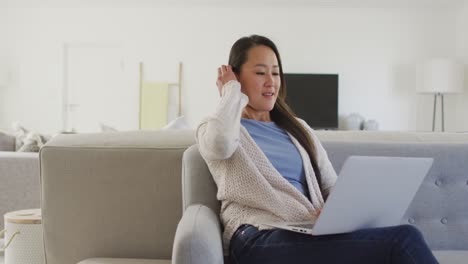 happy asian woman sitting on sofa, resting with tablet at home