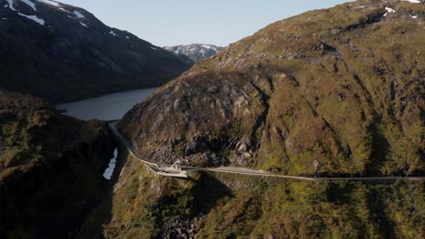 vista aérea, paisaje escénico noruego, carretera en la ladera y lago glacial en un día soleado de verano