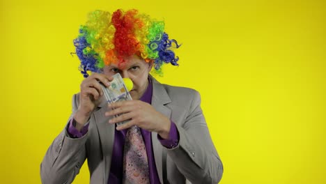 clown businessman entrepreneur boss in wig shows tricks with money banknotes