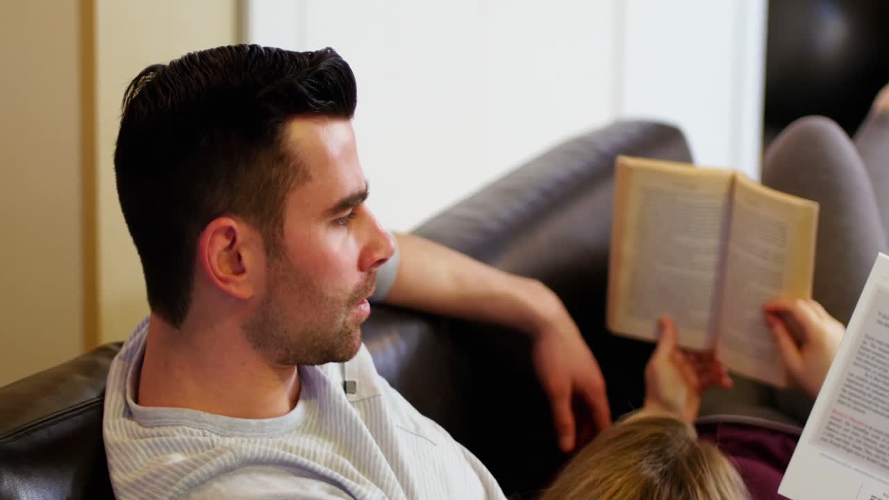 Couple lying on sofa and reading books