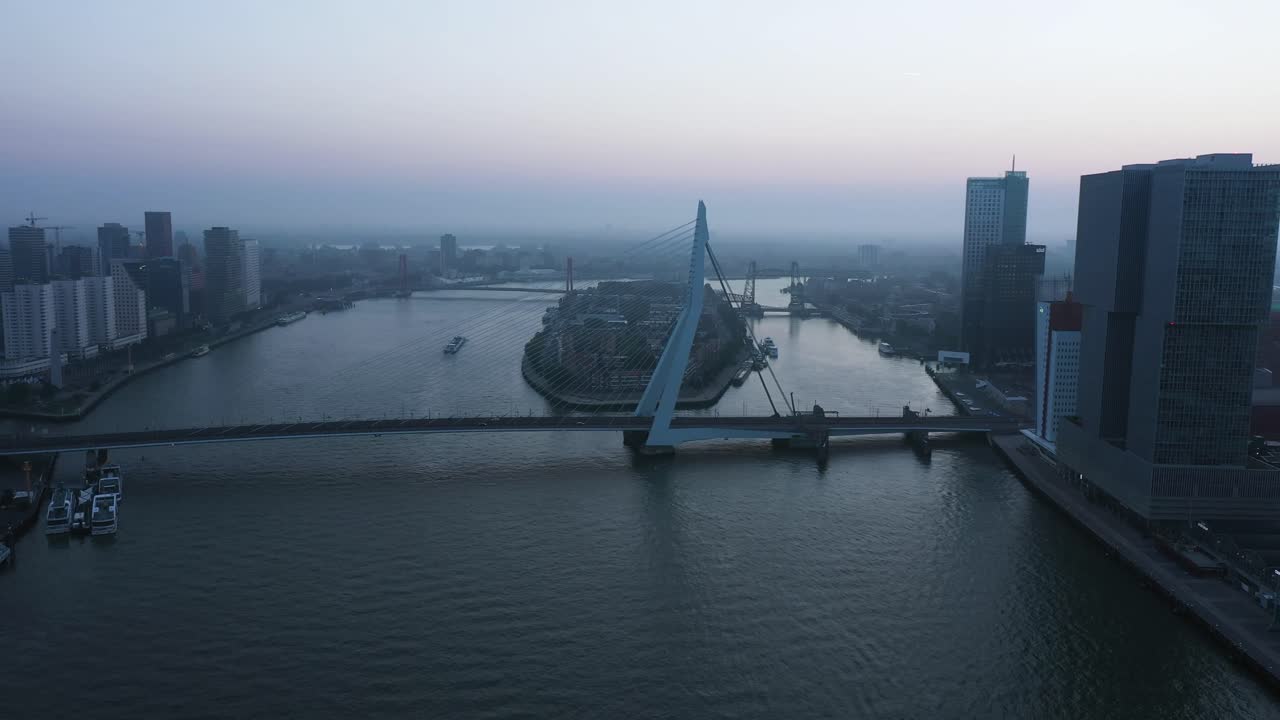 Vista aérea en retroceso del Puente Erasmus y el río durante una mañana con niebla en los Países Bajos