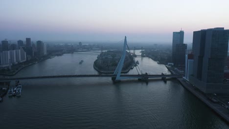 Aerial-backwards-shot-of-Erasmus-Bridge-and-river-during-foggy-morning-in-Netherlands