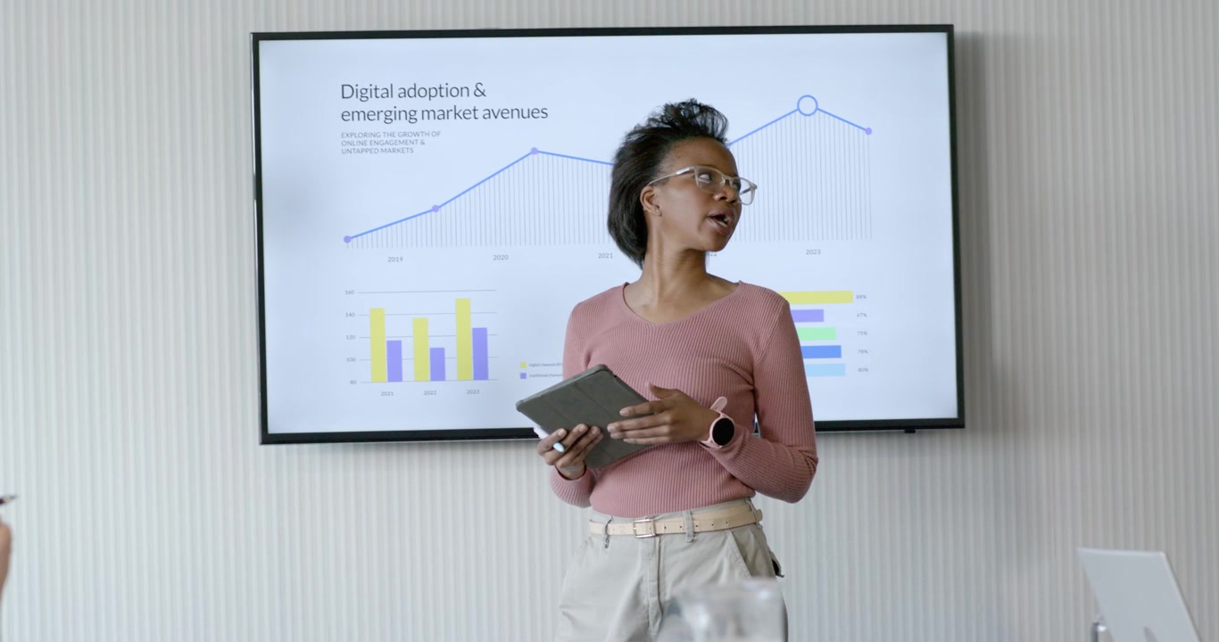 Camera sharpening, adult African woman speaker stepping in office with tablet, pointing at charts
